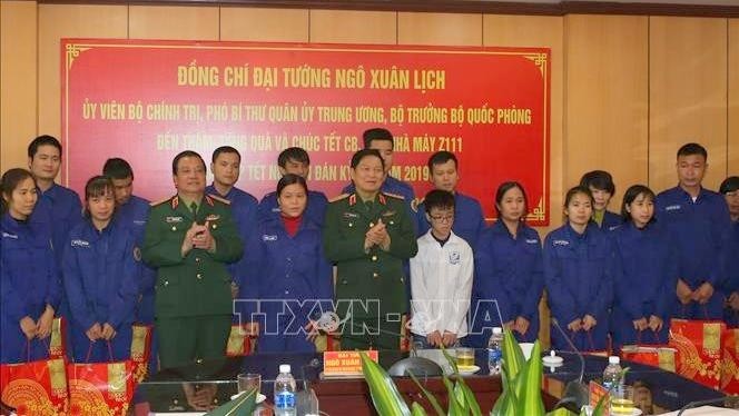 Defence Minister, General Ngo Xuan Lich (fifth from left) presents gifts to disadvantaged workers of the Z111 Factory (Photo: VNA)