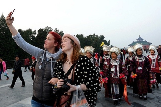Two foreign tourists take pictures in Beijing's Temple of Heaven. (Photo:China Daily)