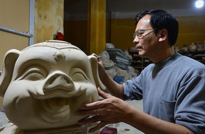 Artisan Vuong The Cuong working on a pottery pig sculpture