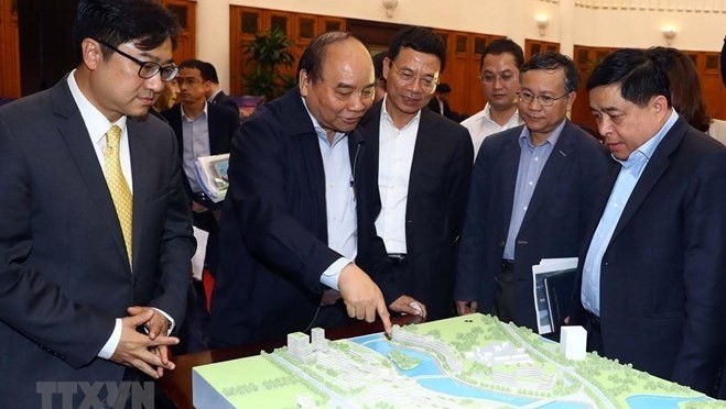 PM Nguyen Xuan Phuc (second from left) and participants examine the model of the National Innovation Centre.(Photo: VNA)