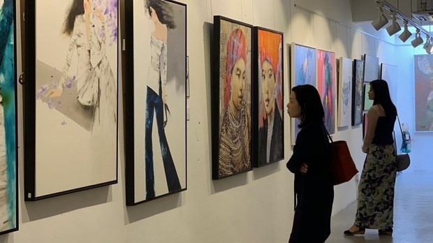 Visitors are enjoying the paintings at the exhibition. (Photo: vietnamplus)