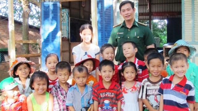 Military captain Tran Binh Phuc and his students posing for a group photo in front of their class on Hon Chuoi island (Photo: baotintuc.vn)