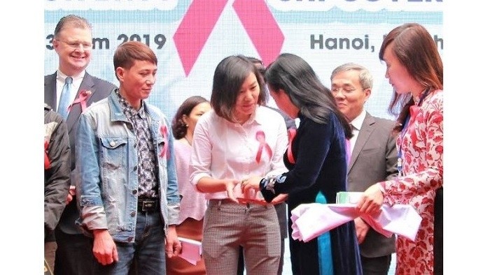Health Minister Nguyen Thi Kim Tien (R) presents ARV drugs from health insurance to patients. (Photo: NDO/Thien Lam)