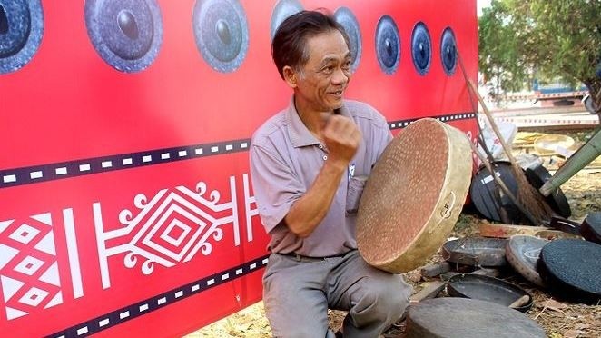 An artisan tests the sound of a gong at the event. (Photo: tienphong.vn)