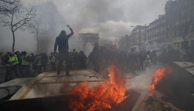 A protester stands on a burning barricade during a demonstration by the "yellow vests" movement in Paris, France, March 16, 2019. (Reuters)