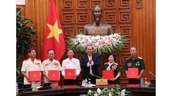 Deputy PM Truong Hoa Binh (in suit) presents gifts to people from Ca Mau province with meritorious services to the nation, who are on a visit to Hanoi, on March 28. (Photo: VGP)