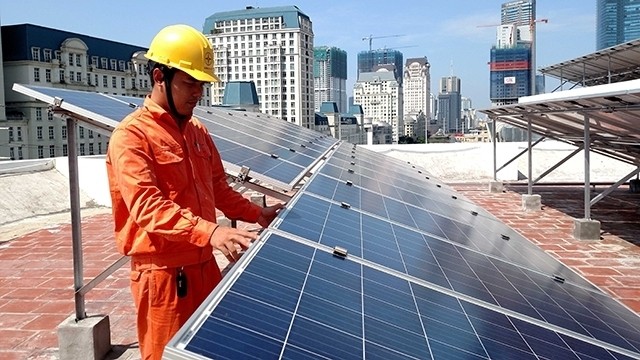 A worker from Hanoi EVN examines a rooftop solar energy system. (Photo: Tuan Hung)
