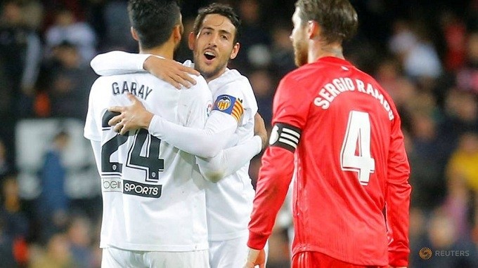 Valencia's Dani Parejo and Ezequiel Garay celebrate after the match as Real Madrid's Sergio Ramos looks on. (Reuters)