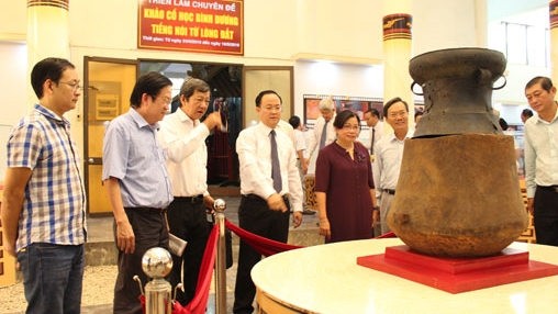 The delegates and visitors are surveying the wooden burial jar with a bronze drum lid. (Photo: baobinhduong.vn)
