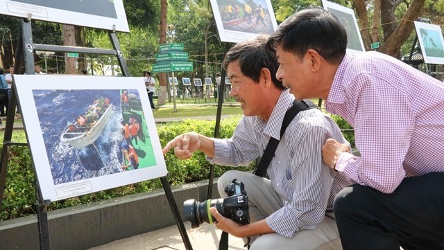 Visitors admiring a photo on display at the exhibition. (Photo: VNA)