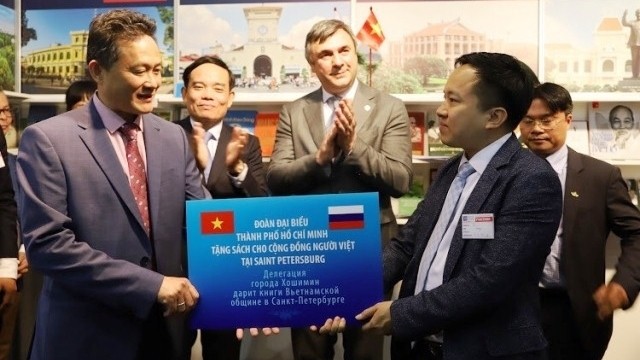 Chairman of the Overseas Vietnamese Community in Saint Petersburg Le Dinh Vu receives books from the Ho Chi Minh City delegation.