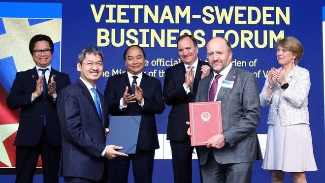 Prime Ministers Nguyen Xuan Phuc (third, left) and Stefan Löfven (third, right) witness the exchange of cooperation documents at the Vietnam-Sweden business forum in Stockholm on May 27 (Photo: VNA)