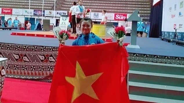 Weighlifter Khong My Phuong poses with the national flag after winning two gold medals at the World Junior Championships. (Photo: VNA)