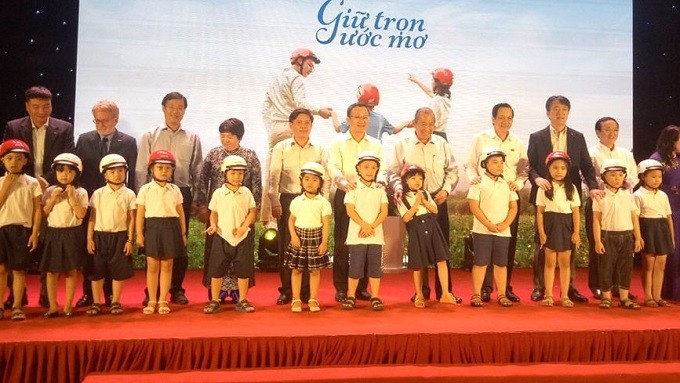 Deputy PM Truong Hoa Binh (fifth from right) and delegates present helmets to the students.