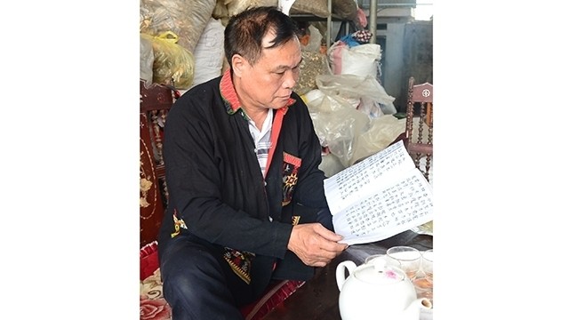 Trieu Phu Duc is reading a book written in the Nom Dao script.