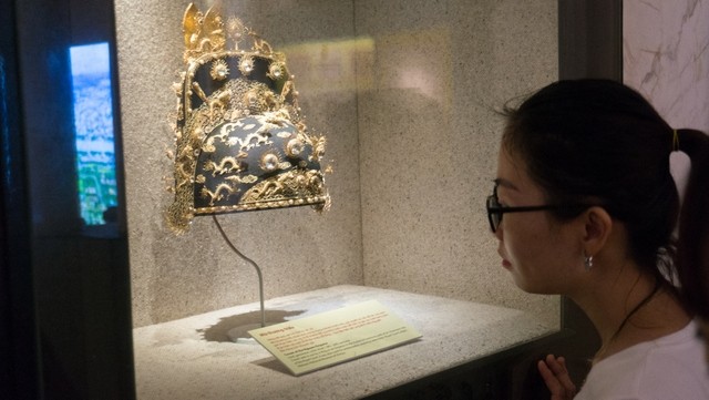 A visitor at the exhibition looks at information describing the crown of the Nguyen Emperor used during the 19th-20th century. (Photo: NDO/Trung Hung)