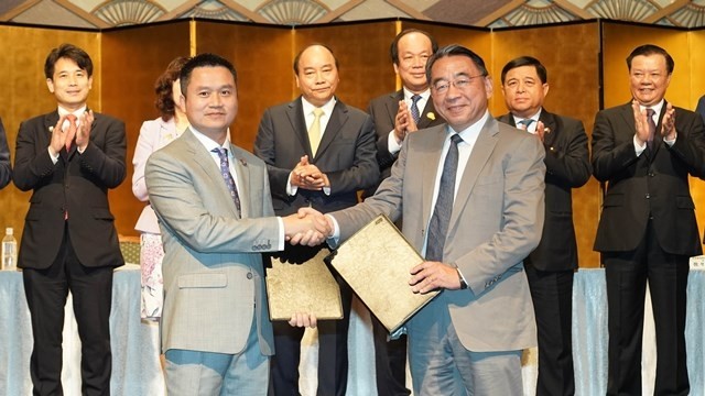 PM Nguyen Xuan Phuc (third, left, behind row) and other officials witness the exchange of cooperation documents between Vietnamese and Japanese businesses at an investment promotion conference in Tokyo on July 1. (Photo: VNA)