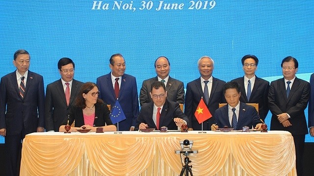 Minister of Industry and Trade Tran Tuan Anh (sitting, first from right) signs the EVFTA between Vietnam and the EU representatives in Hanoi on June 30. (Photo: NDO/Tran Hai)