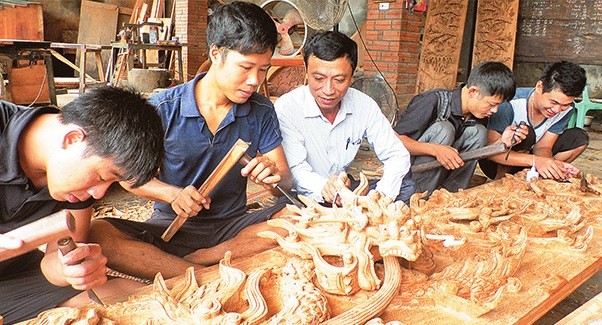 Carpenters in Chang Son village carving wood with engraver tool.