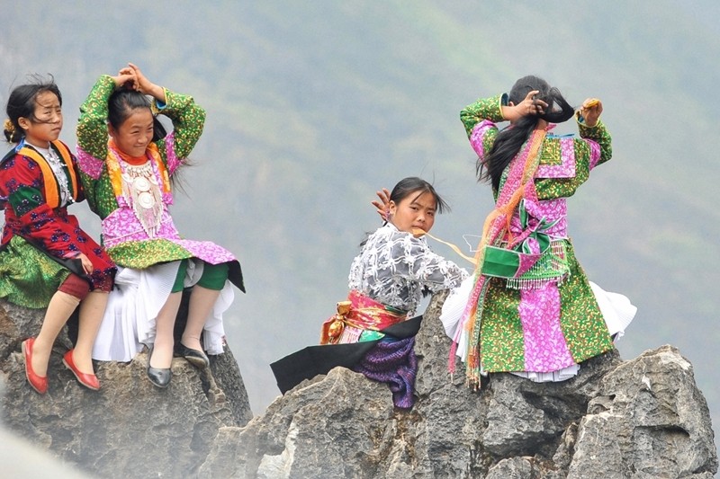 Girls braiding their hair on the edge of the Dong Van stone plateau.