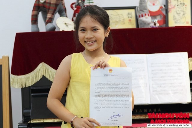 Fifth grader nguyen Nguyet Linh receives a complimentary letter from Minister of Natural Resources and Environment Tran Hong Ha for her proposal of ending balloon release at back-to-school ceremonies  (Photo: baotainguyenmoitruong.vn)