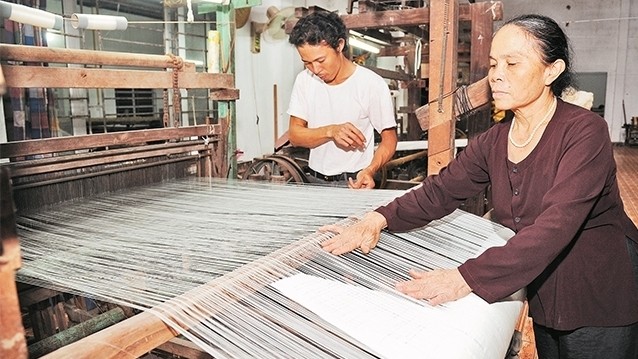 Artisan Phan Thi Thuan inspects silk quality at Phung Xa silk village in Hanoi. (Photo: NDO/Tran Hai)