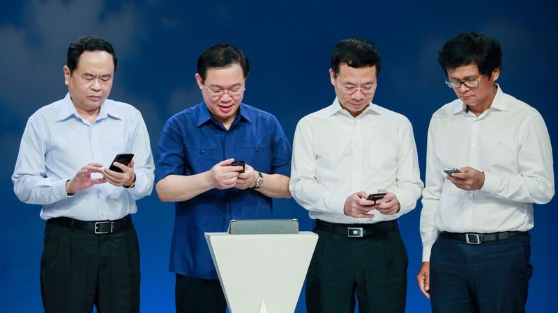 Deputy PM Vuong Dinh Hue (second from left) and other officials send text messages to support the poor. (Photo: DDK)