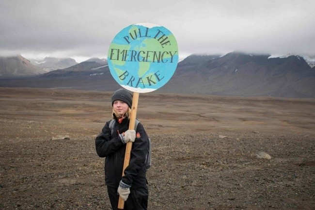 In a photo taken on Aug 18, 2019, an Icelandic girl holds a "Pull the emergency brake" sign near where a monument was unveiled at the site of Okjokull, Iceland's first glacier lost to climate change. (Photo: AFP)