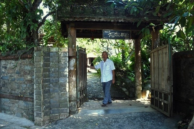 Tich Thien Duong’s owner, Do Huu Minh, standing at an open gate in front of the house