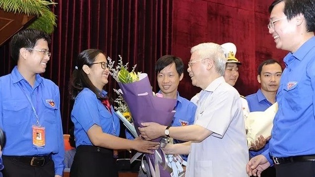 Party General Secretary and President Nguyen Phu Trong presents flowers to the outstanding young Party members at the meeting. (Photo: NDO/Dang Khoa)