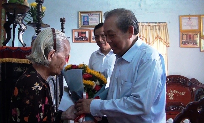 Permanent Deputy PM Truong Hoa Binh presents flowers to Vietnamese Heroic Mother Nguyen Thi Ngay. (Photo: VGP)
