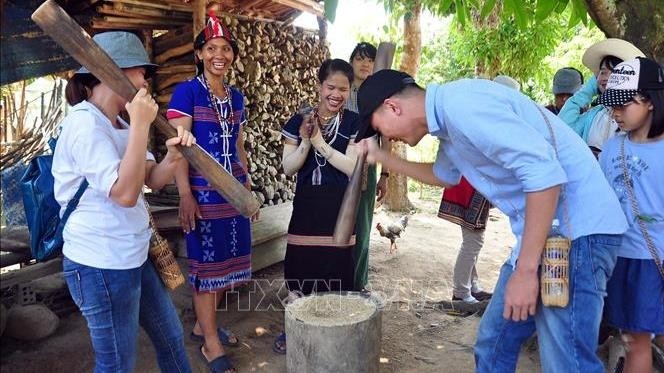 Tourists experience the rice pounding activities of Co Tu ethnic women in Vietnam. (Photo: VNA)