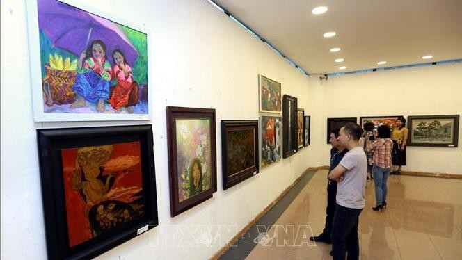 Visitors appreciate artworks about Hanoi at the exhibition. (Photo: VNA)