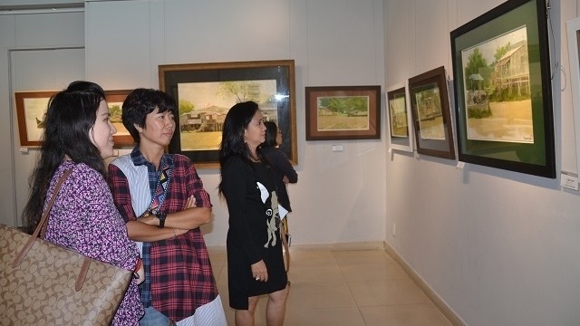 Visitors admiring paintings on display at the exhibition. (Photo: NDO/Manh Hao)