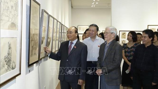 Prime Minister Nguyen Xuan Phuc admiring photos on display at the exhibition 