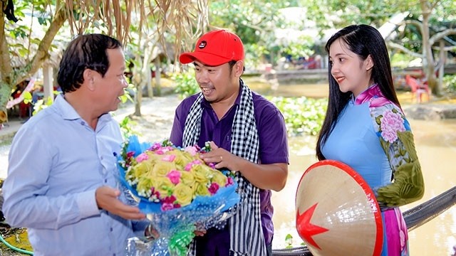 Director of the C2T Media and Tourism Company Vo Van Phong (middle) presents his customers with a flower bouquet made from coconut leaves