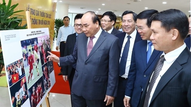 Prime Minister Nguyen Xuan Phuc and delegates visit the show of winning works as part of the 2018 National External Information Service Awards in Hanoi on June 7, 2019. (Photo: VNA)