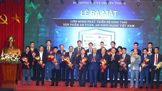 Prime Minister Nguyen Xuan Phuc (first row, seventh from right) and Minister of Information and Communications Nguyen Manh Hung (fifth from right) present flowers to members of the Vietnam Union for Development of Cyber-Security Product Ecosystem.