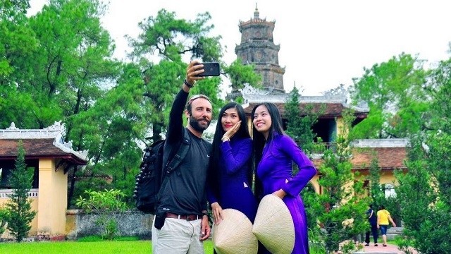 A foreigner takes a photo with two girls from Hue at the Thien Mu Pagoda in Hue City. Entrance fees to relic sites in Vietnam will apply uniformly for both Vietnamese and foreigners, starting from January 13, 2020. (Photo: Le Anh Thi)