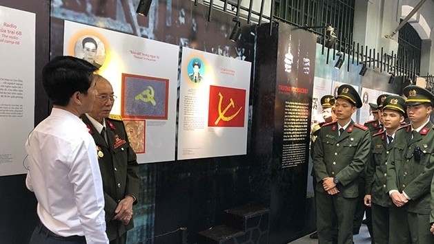 Young soldiers exchange with a senior revolutionary witness at the exhibition held at the Hoa Lo Prison Memorial in Hanoi. (Photo: NDO/Tuyet Loan)