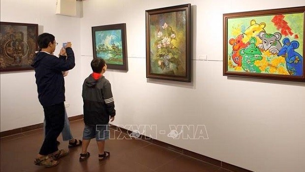 Visitors admire photos on display at the exhibition (Photo: VNA)