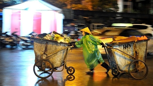 A worker of the Hanoi Urban Environment Company (URENCO) moving garbage carts on Lunar New Year’s Eve.