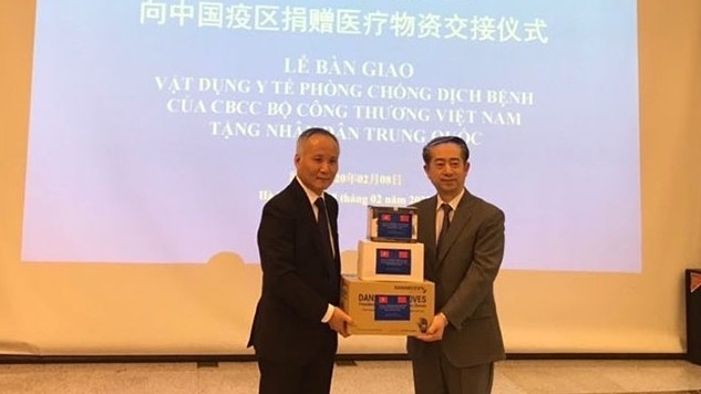 Deputy Minister of Industry and Trade Tran Quoc Khanh (L) hands over medical equipment and supplies to Chinese Ambassador to Vietnam Xiong Bo 