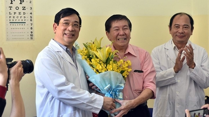 The 73-year-old patient (pink shirt) and dcotors pose for a photo when he is discharged from hospital on February 21 afternoon. (Photo: NDO/Duyen Phan)