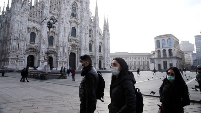 People wearing protective masks walk past the Duomo in Milan on February 23. (Photo: AP)