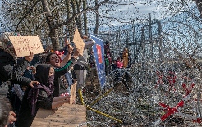 Migrants hold placards as they demonstrate, waiting at the buffer zone in front of the Pazarkule border crossing to Greece (Source: AFP via Getty Images)