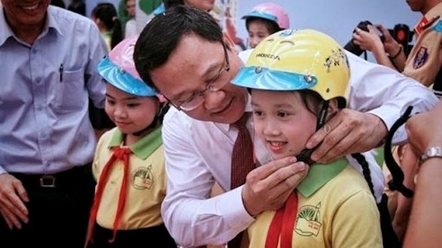 Deputy Head of the National Traffic Safety Committee, Khuat Viet Hung, wears a helmet to a pupil. (Photo: National Traffic Safety Committee)