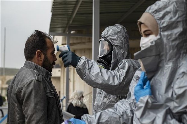   Medics check body temperature of passengers upon their arrival by bus in Syria's Kurdish area from Iraqi Kurdistan via the Semalka border crossing in Syria on March 1. (Photo: AFP/VNA)