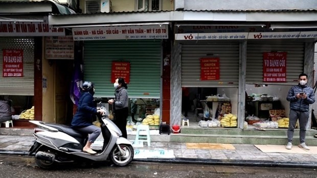 Stores on Hanoi's Luong Van Can Street half close their doors, only serve take-aways or online orders due to the impact of COVID-19 (Photo: VNA)