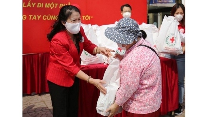 Chairwoman of the Vietnam Red Cross Society Nguyen Thi Xuan Thu (L) presents gifts to disadvantaged people affected by COVID-19. (Photo: Vietnam Red Cross Society)